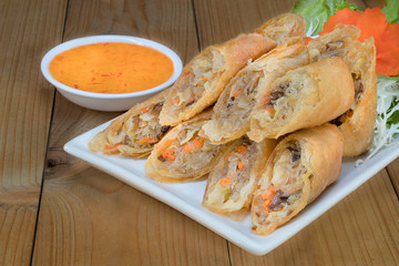 Veg. Spring Rolls on white dish on wooden table.Thai food and selective focus.