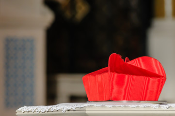 A cardinal's Beretta hat sits on a table during a requiem mass