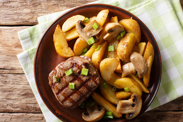 Juicy fillet mignon with fried potato wedges and mushrooms close-up. horizontal top view