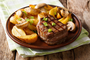 Juicy fillet mignon with fried potato wedges and mushrooms close-up. horizontal