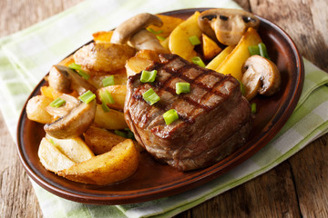 fillet mignon with fried potatoes and mushrooms close-up on a plate. horizontal