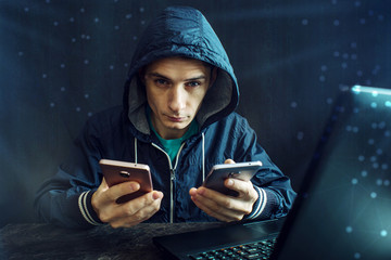 Male hacker uses the mobile phone to hack the system. Concept of cyber crime and hacking electronic...