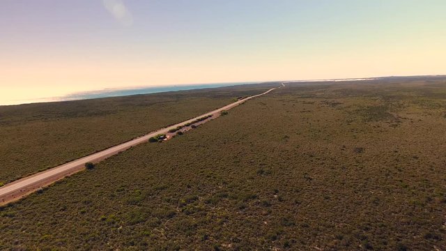 Flug über Vegetation in West-Australien mit Kamerabewegung auf einen Highway zu und einem Meerabschnitt im Hintergrund