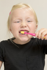 Little Girl Brushing Her Teeth with a Pink Toothbrush