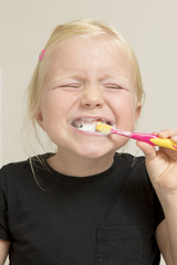 Smiling Little Girl in Black Shirt Brushing Her Teeth