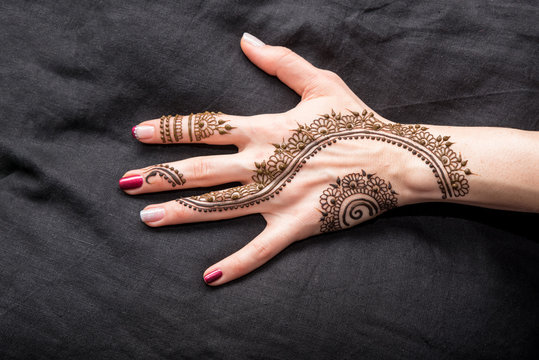 Picture of human hand being decorated with henna