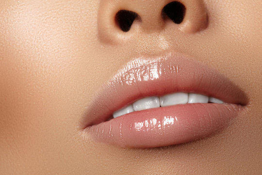 Moisturizing lip balm, lipstick. Close-up beautiful sexy wet lips. Full lips with gloss lip makeup. Filler Injections