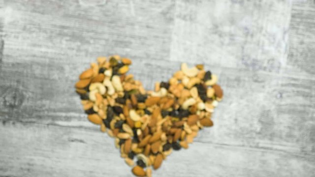 Mix of healthy raw nuts in heart shape on wooden background. Healthy organic snack