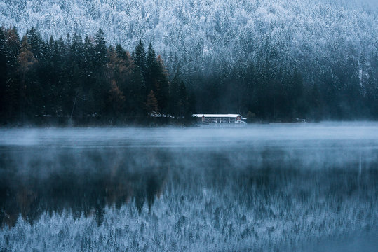 Boat house at Lake Eibsee with pine forest during early winter on a blue hour moody day, bavaria, Germany