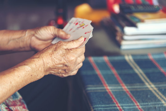 Active retirement, old people and seniors free time, selected focus on old women wrinkle hands having fun and playing cards game at home.