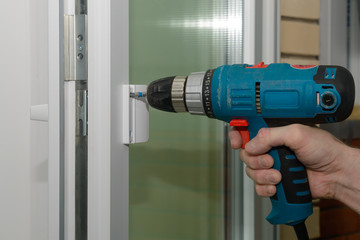 fastening the handle to the plastic door with electric screwdriver