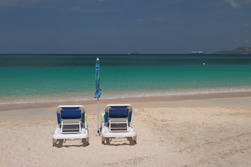 Fototapeta na wymiar Beach chaise lounges on seashore. St. George's, Grenada