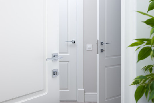 Open the white door into the corridor. Chrome modern door handles