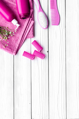 Hair washing and styling tools. Comb, shampoo, hairspray, curlers on white wooden background top view copyspace