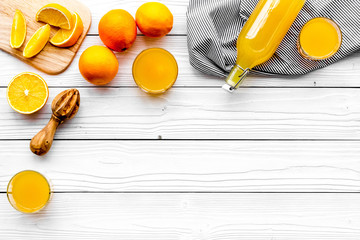 Make orange juice. Juicer, beverage in bottle and glasses near slices of oranges on white wooden background top view copyspace