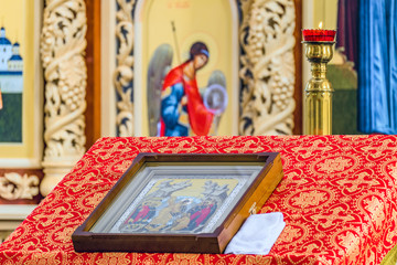 Russian Orthodox Church. Burning Church candlestick with a burning candle above pulpit with an icon for liturgy, prayers and sermons. Selective focus.