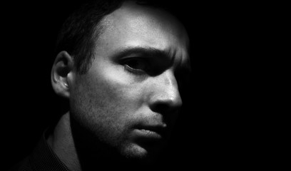 Young man face black background, low key