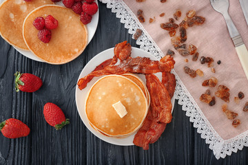 Delicious pancakes served with raspberries and bacon on table, top view