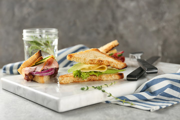 Board with delicious sandwiches on table