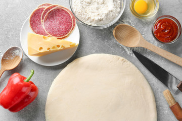 Raw dough and ingredients for pizza on table