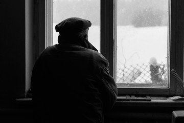 Lonely senior man looking out the window