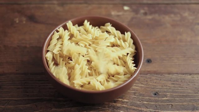 raw twisted pasta is poured into a clay plate