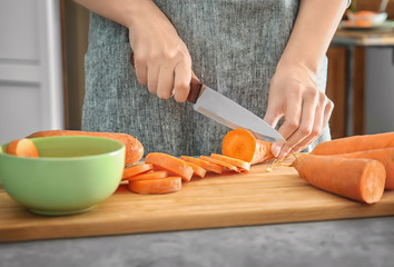 Woman cutting carrot on table, closeup