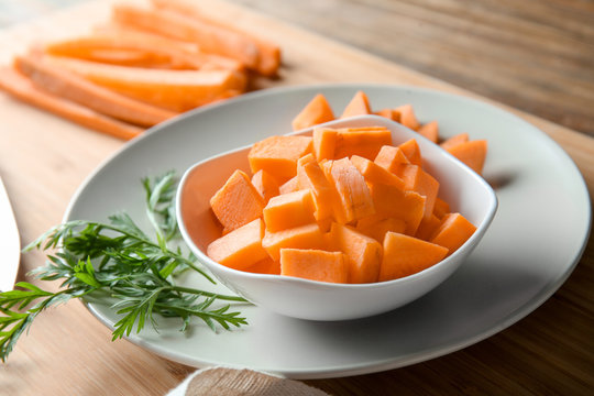 Bowl with cut carrot on table, closeup