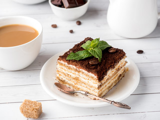 Tiramisu Dessert with Mint and Cup of Coffee on White Wooden Table