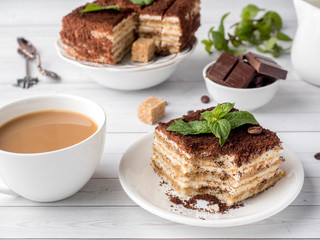 Tiramisu Dessert with Mint and Cup of Coffee on White Wooden Table