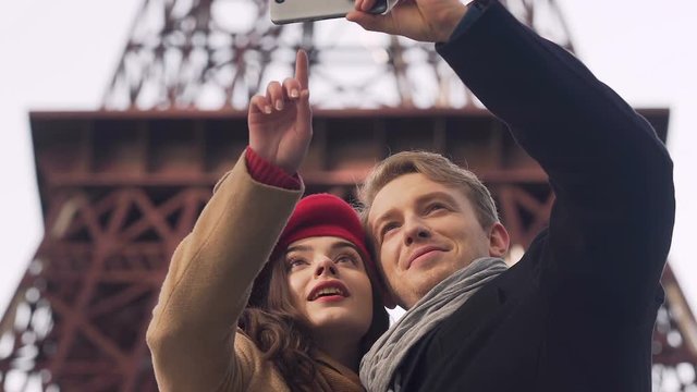 Happy couple taking selfie against background of Eiffel Tower, travel memories