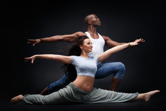Black man and white woman in a beautiful dance position on a black background.