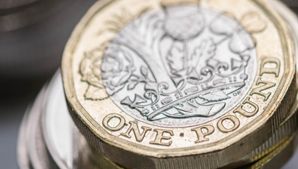 Close up focus photos of new United kingdom Pound coin, among other British coins