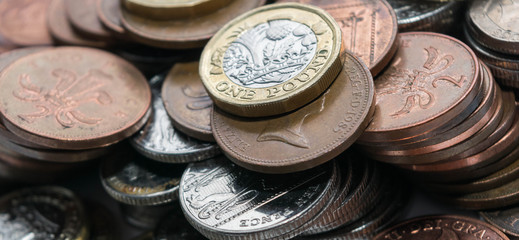 Close up focus photos of new United kingdom Pound coin, among other British coins