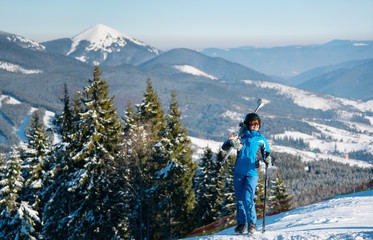 Female skier standing on top of a hill enjoying beautiful scenery on the background copyspace winter snow mountains nature recreation resort