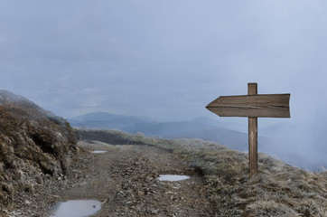 Wooden direction sign in dark mist