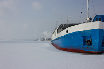 The ship is in a snow captivity. Ship in the ice on the river. The frozen river has a beautiful background.