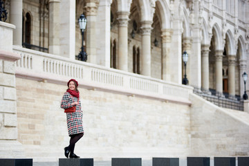 Fototapeta na wymiar Tender female smiling standing against the background of the great architecture of the city of Budapest. Palace of Parliament in Budapest, Hungary. Autumn
