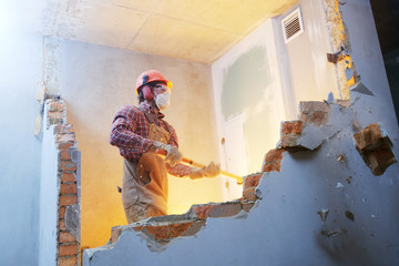 worker with sledgehammer at indoor wall destroying - obrazy, fototapety, plakaty