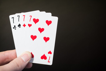 Abstract: man hand holding playing card four seven isolated on black background with copyspace