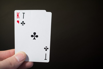 Man hand holding two playing card ace of clubs and and kind isolated on black background with copyspace