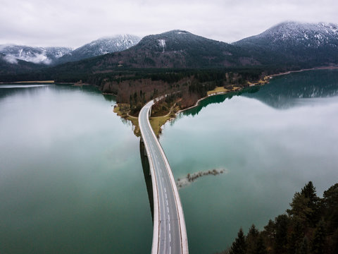 Aerial shot of lake Sylvenstein and it's bridge on a cloudy autumn day with mountains in in background