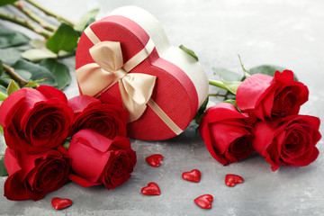 Bouquet of red roses with gift box on grey wooden table