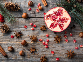 Pomegranate spruce branches star anise nuts, cinnamon and winter spices on wooden background,...