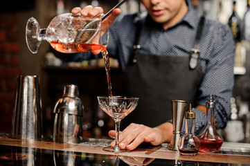 Bartender pours sweet cocktail in bocal