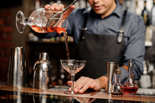 Bartender pours sweet cocktail in bocal