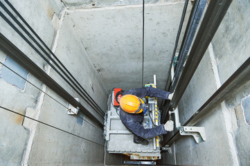 lift machinist repairing elevator in lift shaft - obrazy, fototapety, plakaty