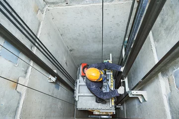 Fotobehang lift machinist repairing elevator in lift shaft © Kadmy