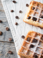 Soft Viennese Belgian waffles with powdered sugar and coffee beans on rustic wooden background
