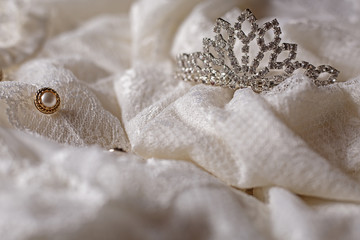 Wedding crown and pearls on white textile